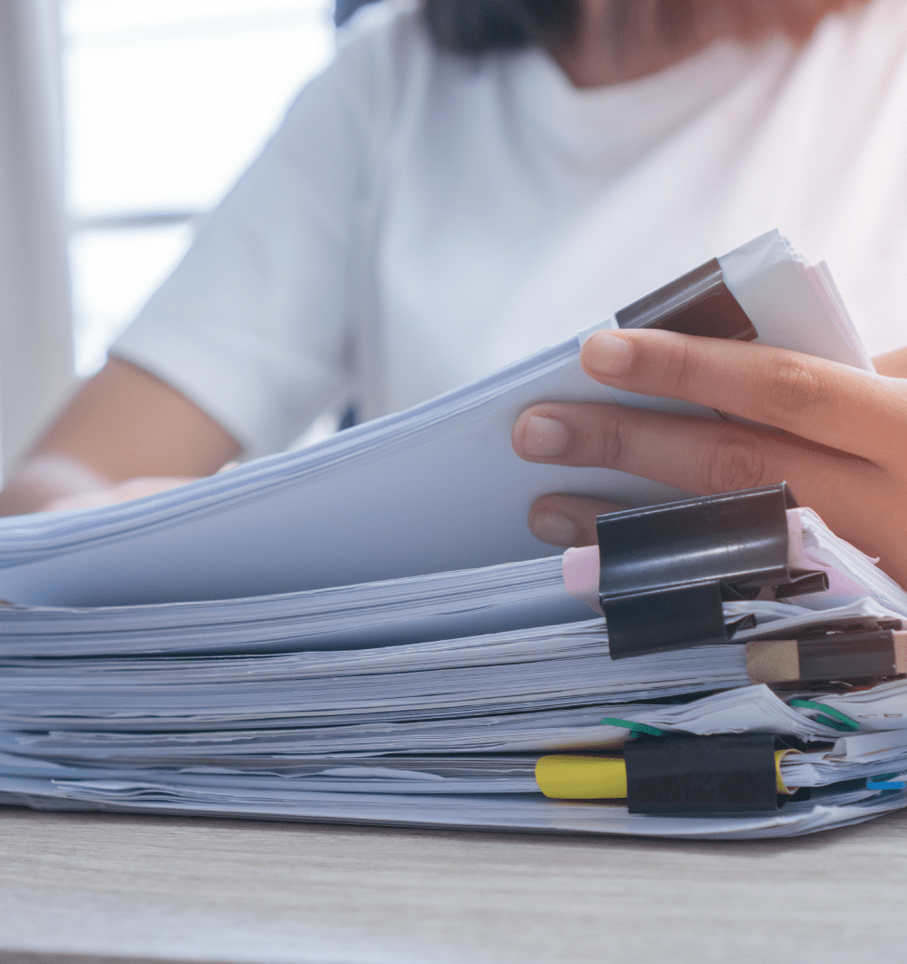 Student holding the top batch of papers from a pile of papers grouped with paper clips